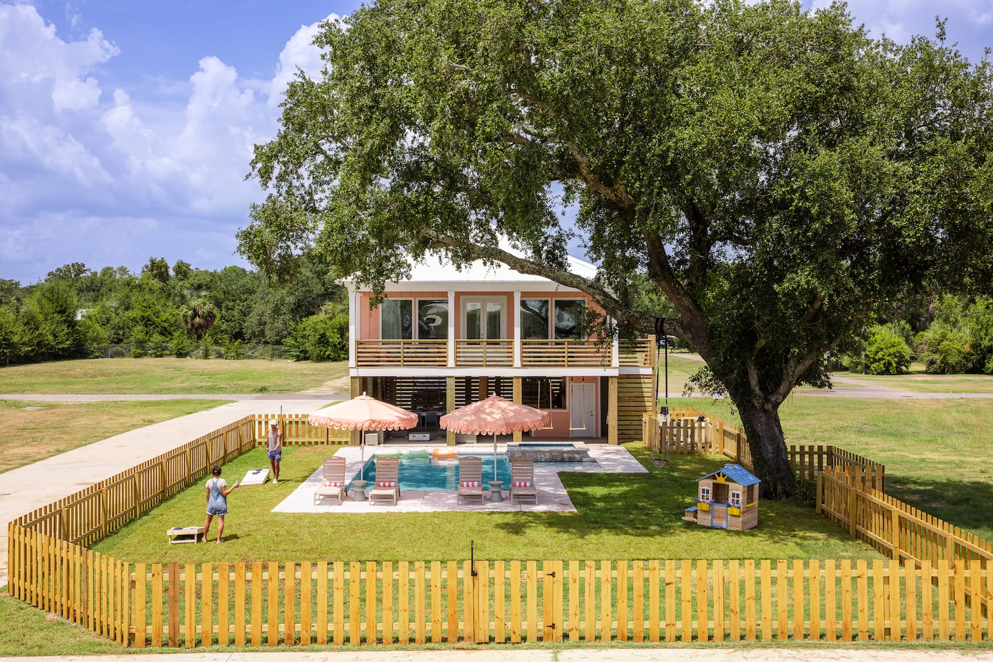 Private backyard with pool, spa, peach umbrellas and a playhouse